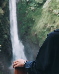 Close-up of woman against waterfall in forest