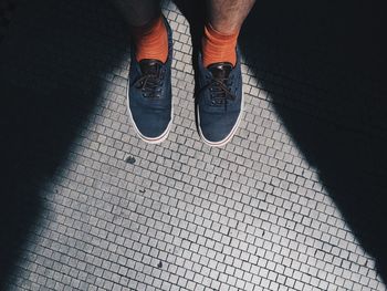 Low section of man standing on tiled floor