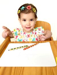 Portrait of girl by table with pencils and paper