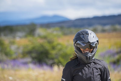 Woman in motorbike clothes and helmet laughing at camera, puerto natal