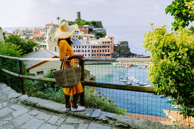 Full length of woman standing by railing against sky