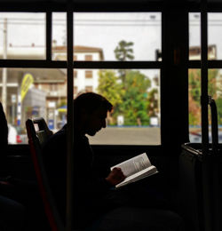 Side view of man reading book in bus