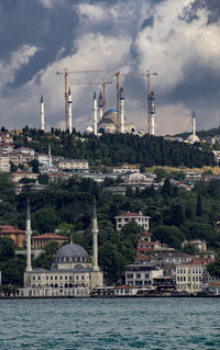 View of factory by buildings against sky