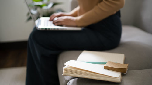 Midsection of woman reading book at home