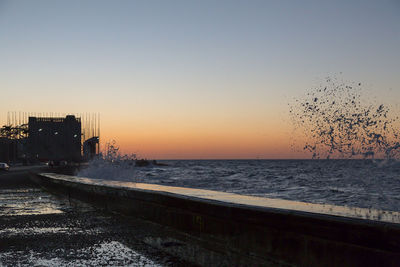 View of calm sea against clear sky at sunset