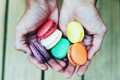 Close-up of hand holding multi colored macaroons