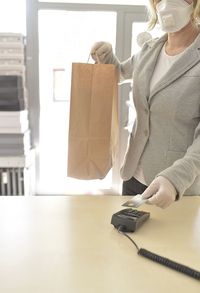 Midsection of woman holding camera at home