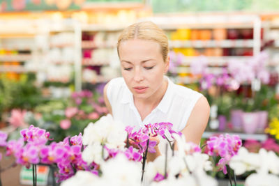 Close-up of mid adult woman sitting by purple flowering plants