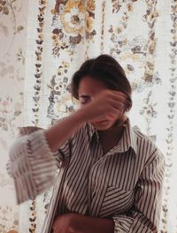 Young woman standing against curtain at home