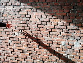 Full frame shot of brick wall with shadow of a human hand
