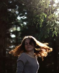 Woman with tousled hair against trees