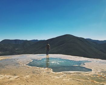 Man standing on mountain against clear blue sky