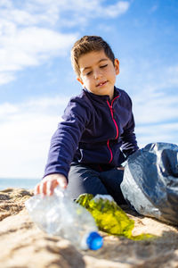 Little kid picking plastic on the beach. recycling concept