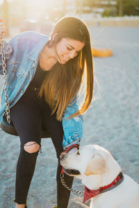 Woman sitting on swing with dog at playground during sunset