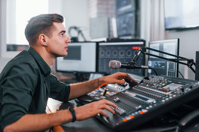 Young man is indoors in the radio studio is busy by broadcast.