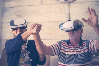 Senior couple wearing virtual reality simulator against wall