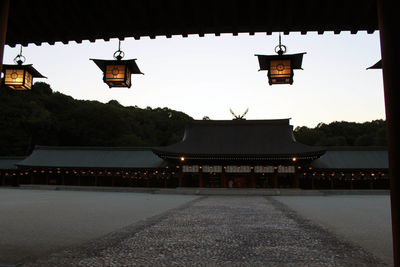 Illuminated lantern by building against sky