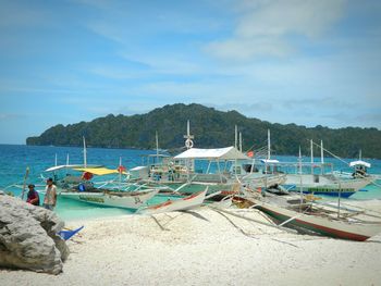 Boats moored at beach against sky