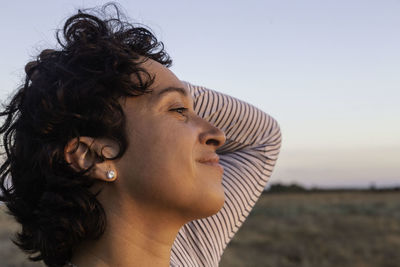 Close-up of young woman looking away against sky