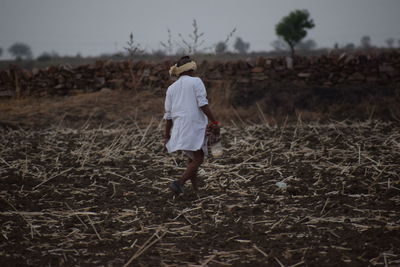 Rear view of man walking on field at dusk