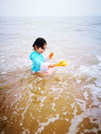 High angle view of girl playing in sea against sky