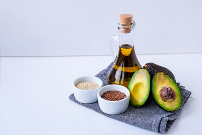 Olive oil in glass bottle with sesame and flax seeds. fresh ripe hass avocado. healthy eating. vegan