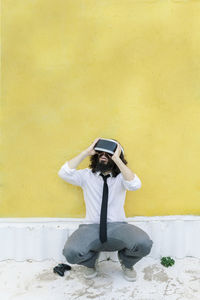 Man photographing with umbrella standing against yellow wall