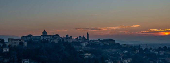 Buildings in city against sky during sunset