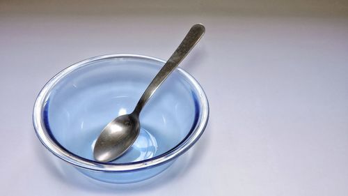 High angle view of spoon in glass bowl on white background