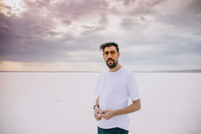 Portrait of man wearing sunglasses standing against cloudy sky