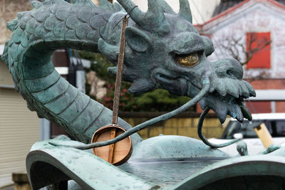 Basin with japanese dragon statue and wooden dipper for water purification
