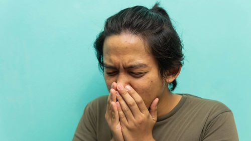 Close-up of man coughing against blue background