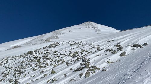 Scenic view of snow covered mountain against blue sky