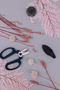 High angle view of pink and white dried flowers, floral design tools on a grey background
