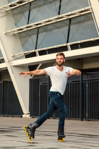 Full length portrait of young man standing against built structure