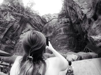 Rear view of woman sitting on rock