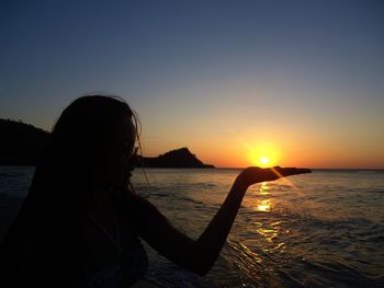 Rear view of silhouette man in sea against sunset sky