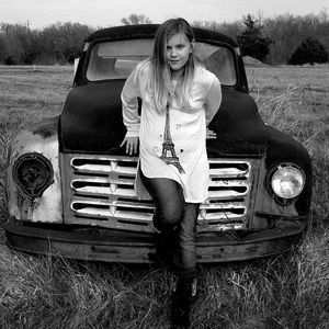 Portrait of young woman leaning on vintage car at field