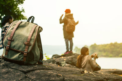 Backpack on rock with people looking at river