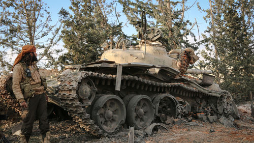 Abandoned vehicle on field against trees