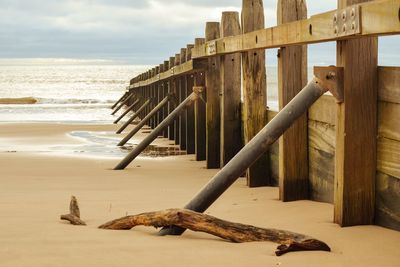 Wooden posts on beach against sky