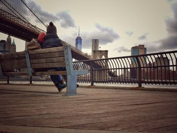 Woman on footbridge against sky