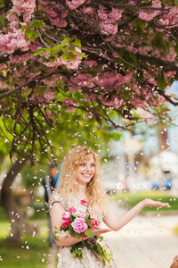 Woman standing by pink flowering plants