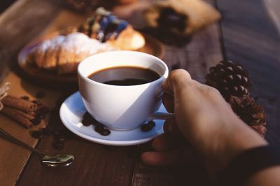 Cropped hand of woman holding coffee on table