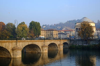 Bridge over river in city against sky