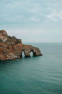 Rock formation by sea against sky