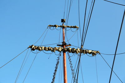 Low angle view of electricity pylon against clear blue sky