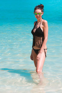 Young woman in bikini standing by swimming pool