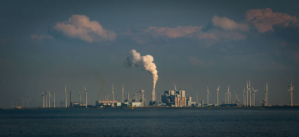 Smoke emitting from factory against sky