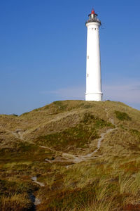 Low angle view of lighthouse amidst buildings against sky